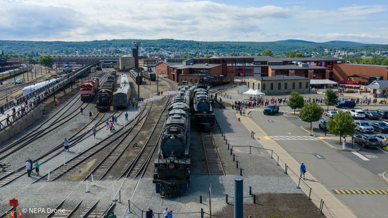 Locomotives lined up in a rail yard with crowds
